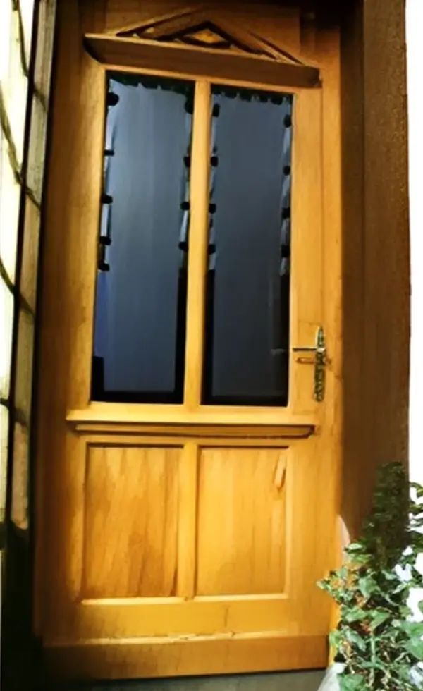 Eine sanierte und naturfarbene antike Eingangstür aus Holz.